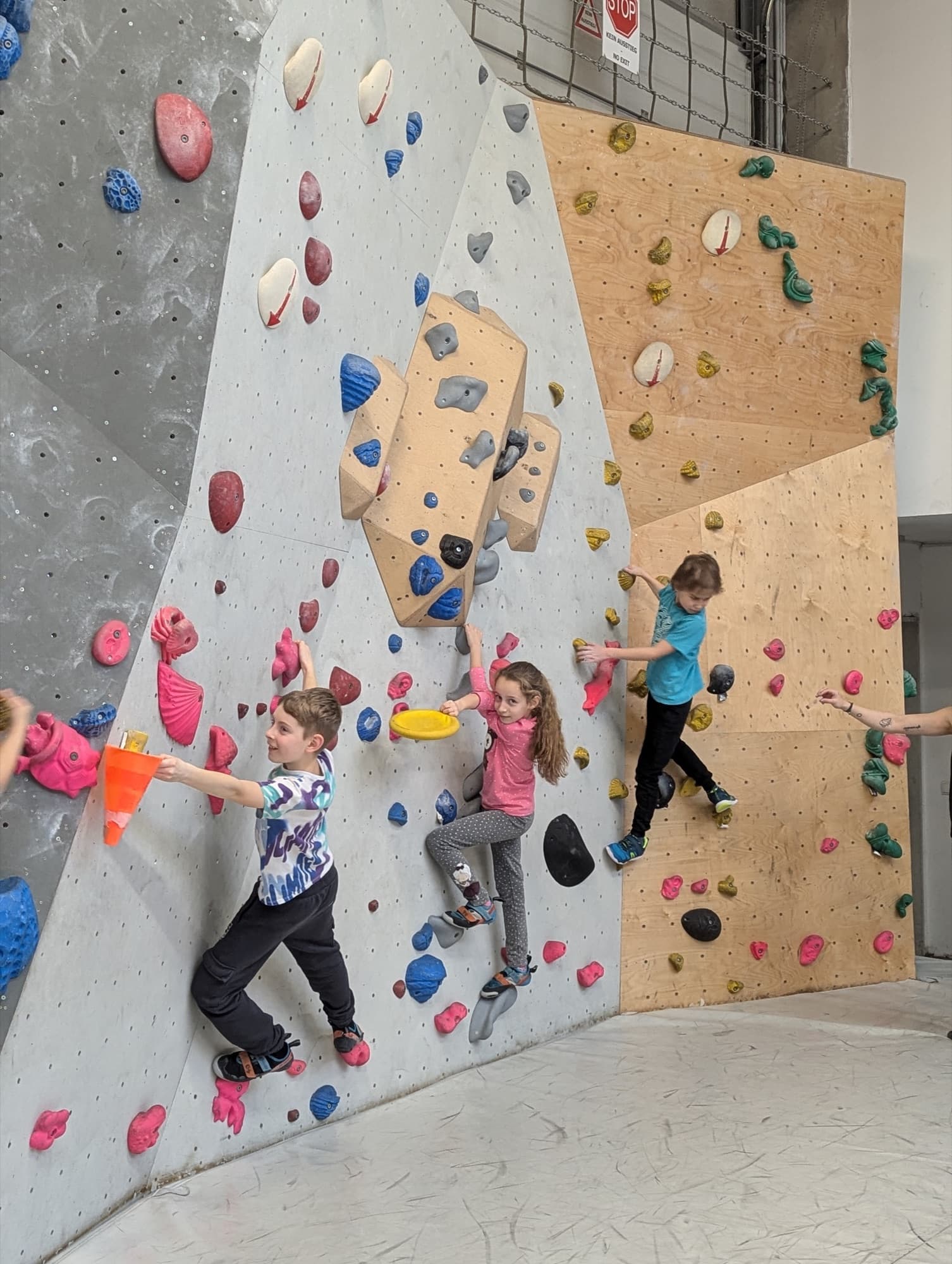 Kinder klettern gemeinsam an der Boulderwand.