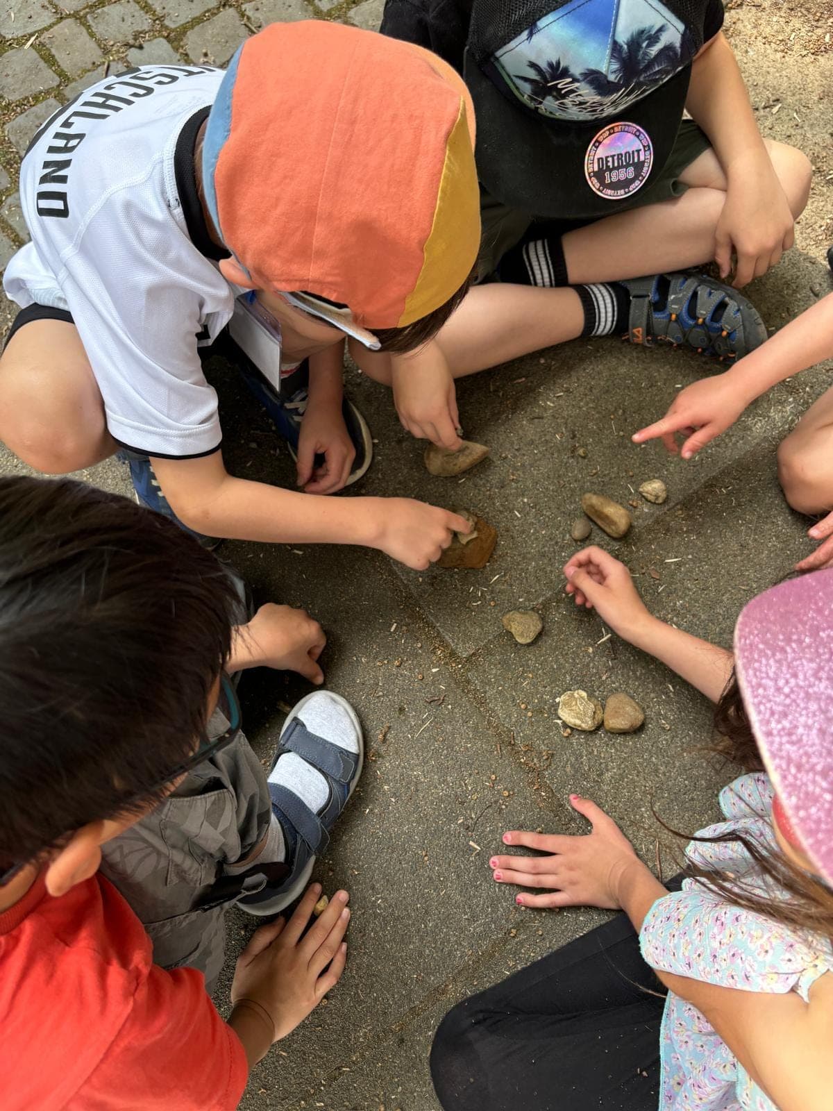Kinder betrachten bei einem Ferien-Workshop gemeinsam gesammelte Steine.