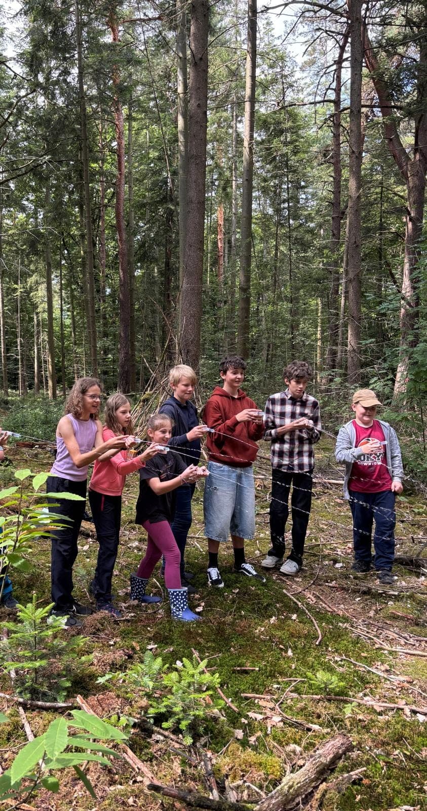 Jugendliche spielen bei einem erlebnispädagogischen Angebot im Wald.