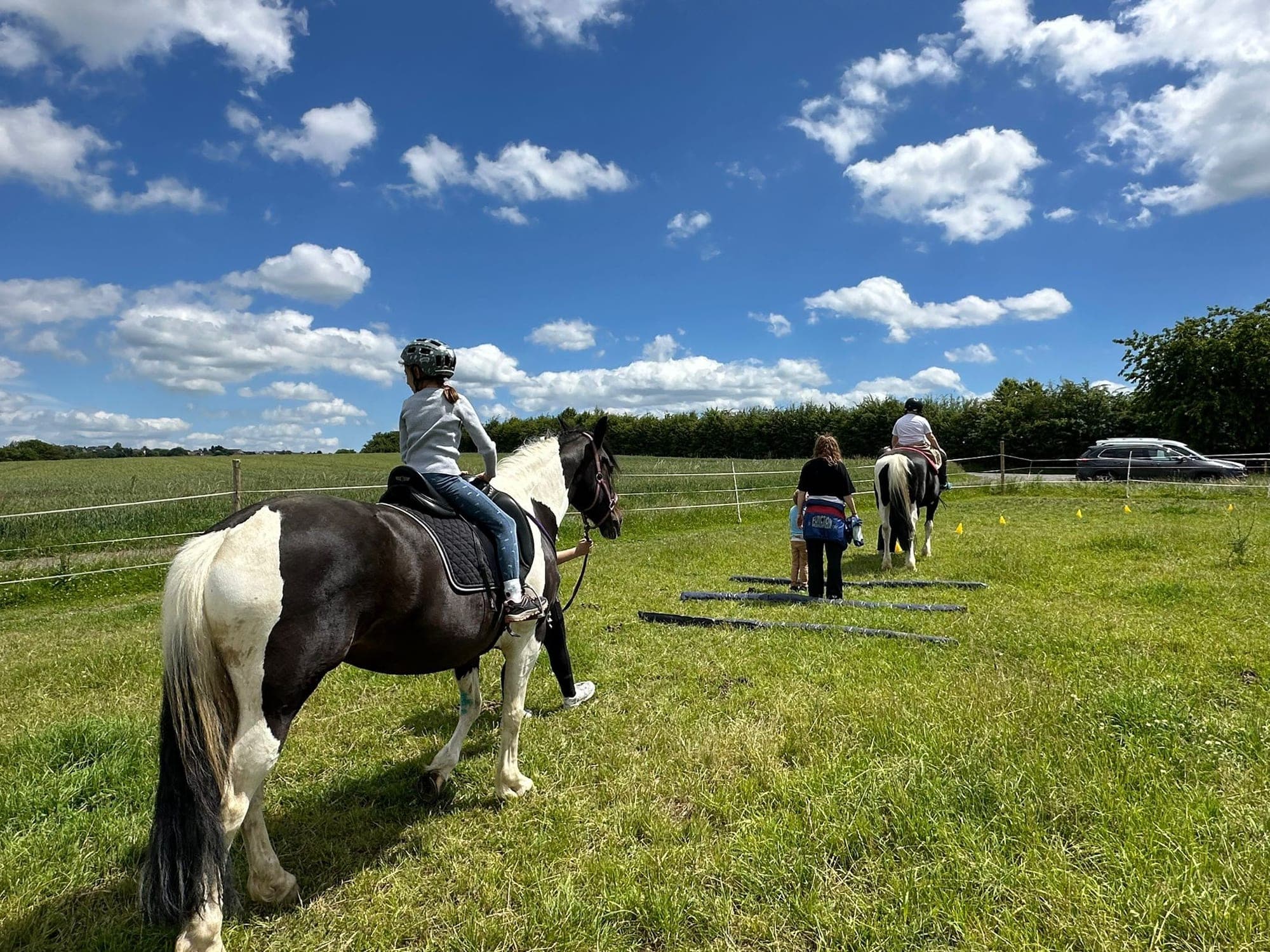 Kinder reiten bei der Reitpädagogik über eine eingezäunte Wiese.