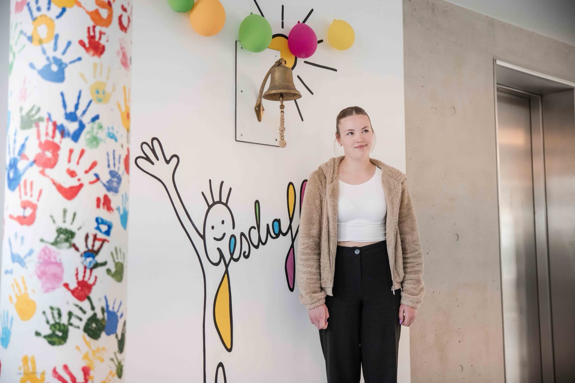 Eine Patientin an der „Geschafft“-Wand mit der symbolischen Glocke